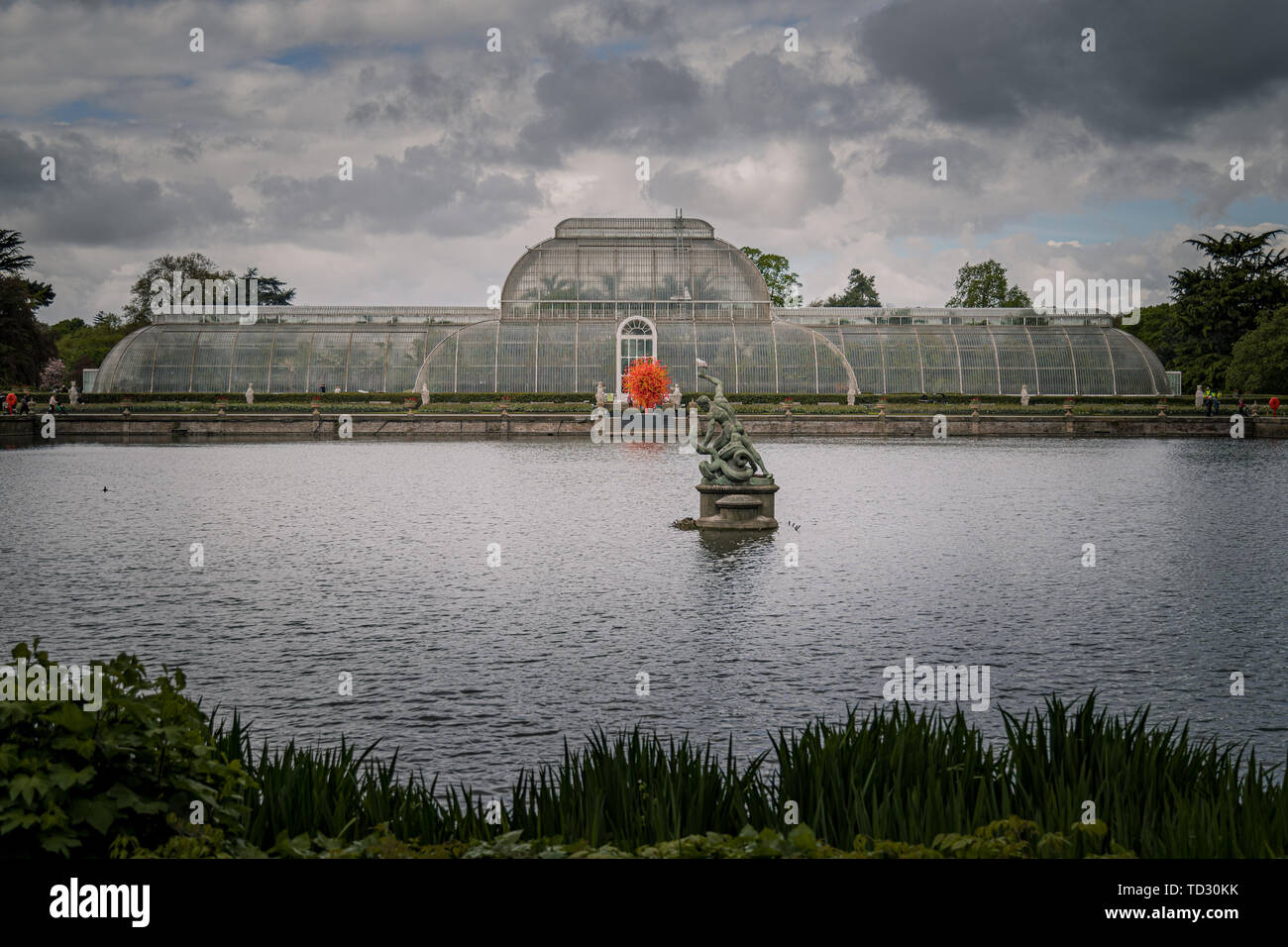 La vista della Casa delle Palme di tutta l'acqua a Kew Gardens con il vetro soffiato scultura sole estivo di Dale Chihuly davanti ad esso. Foto Stock