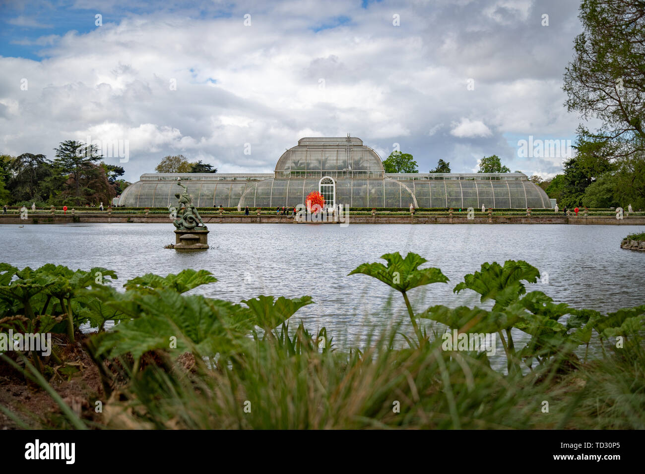 La vista della Casa delle Palme di tutta l'acqua a Kew Gardens con il vetro soffiato scultura sole estivo di Dale Chihuly davanti ad esso. Foto Stock