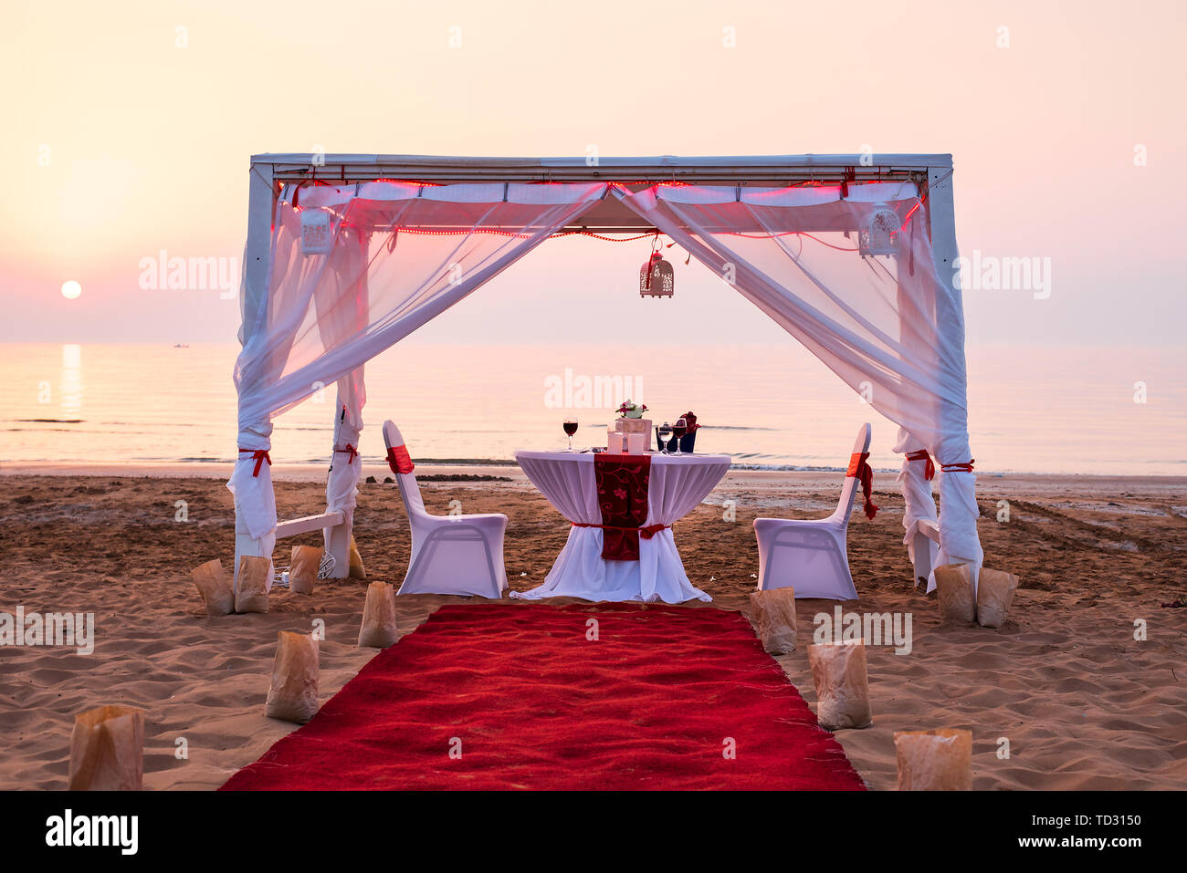 Il Cabana e cena romantica impostazione su una spiaggia al tramonto Foto Stock