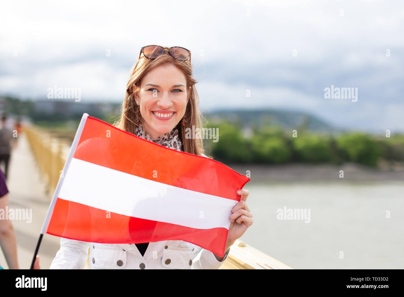 Felice giovane donna naturali azienda bandiera dell'Austria con sorriso toothy all'aperto Foto Stock