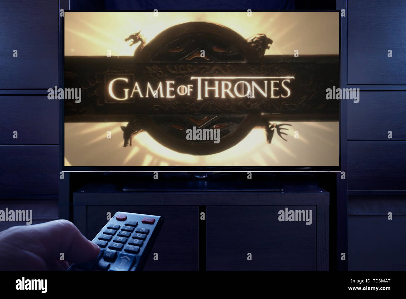 Un uomo punti un telecomando TV al televisore che visualizza il gioco dei troni a titolo principale schermo (solo uso editoriale). Foto Stock