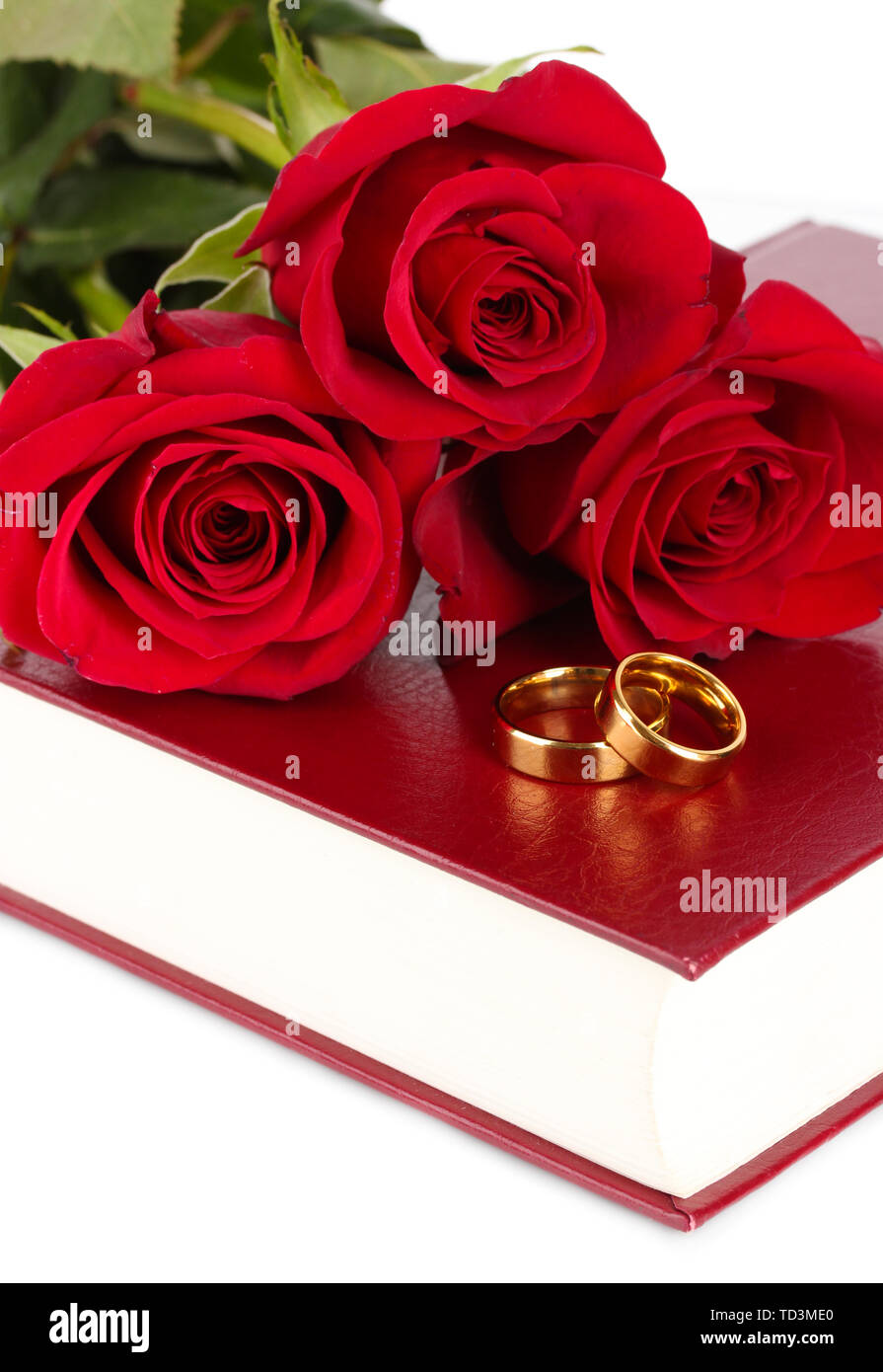 Gli anelli di nozze con rose sulla bibbia isolato su bianco Foto Stock