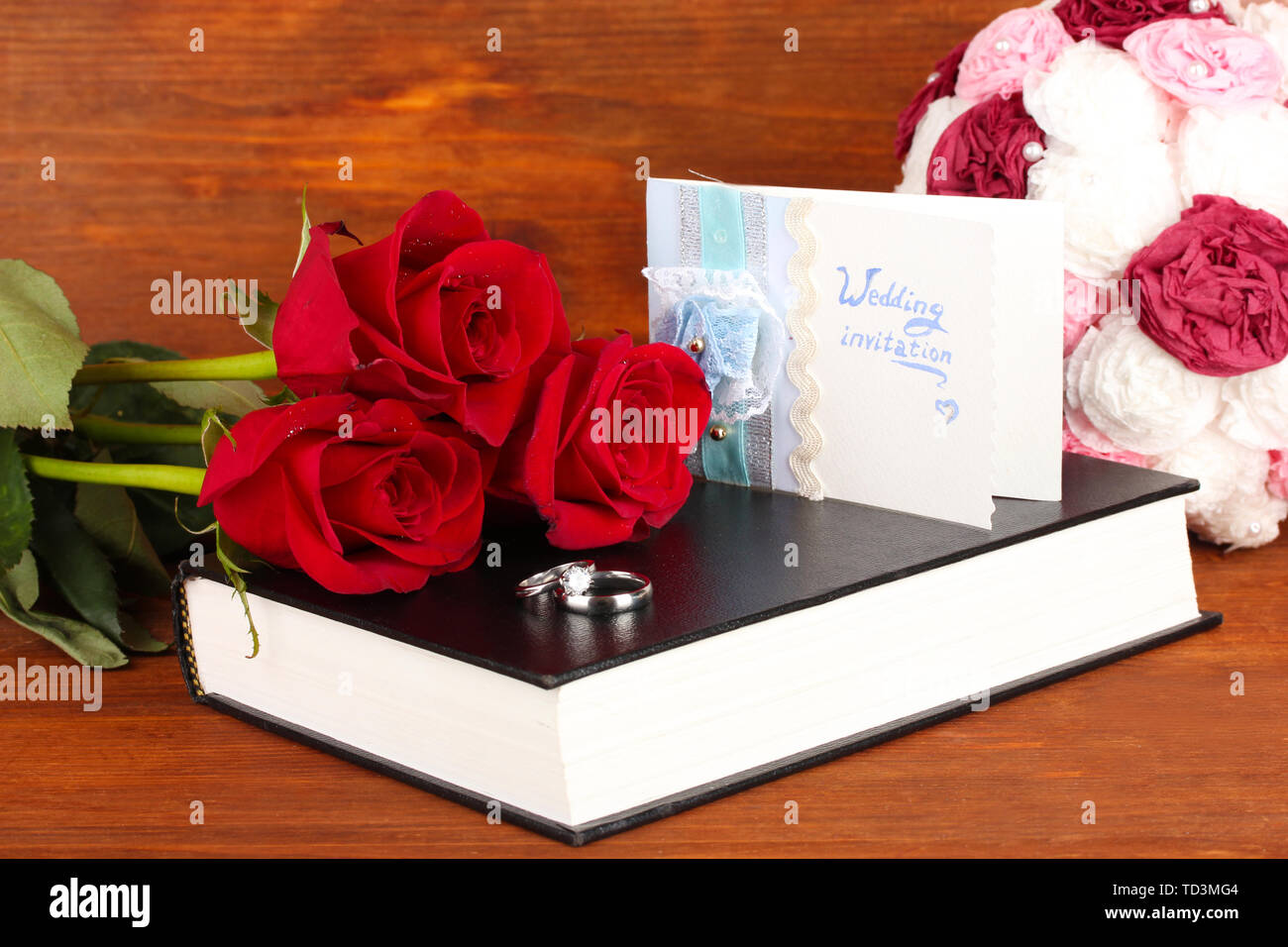 Gli anelli di nozze con rose sulla Bibbia su sfondo di legno Foto Stock
