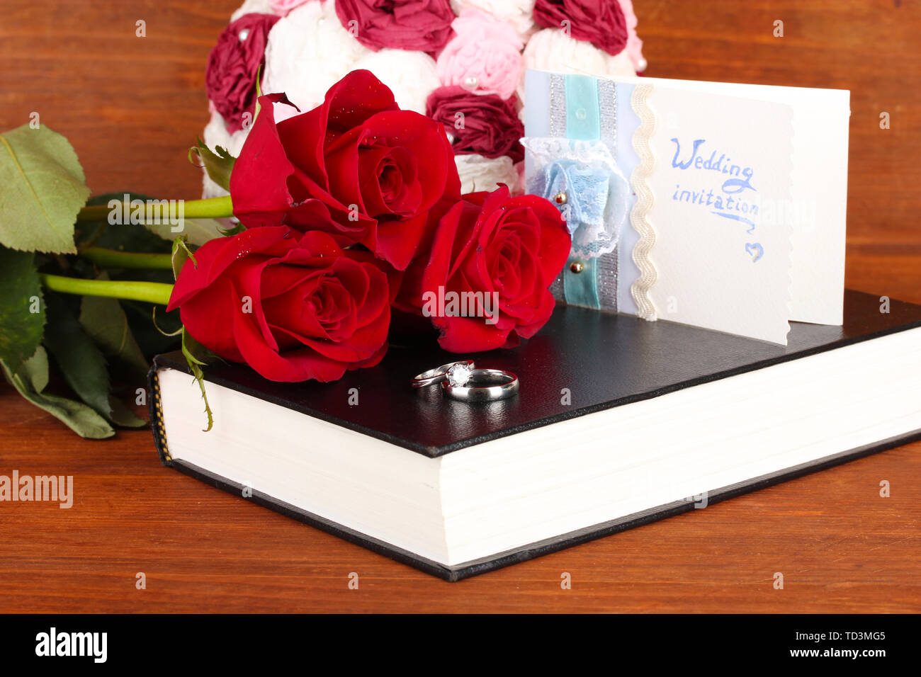 Gli anelli di nozze con rose sulla Bibbia su sfondo di legno Foto Stock