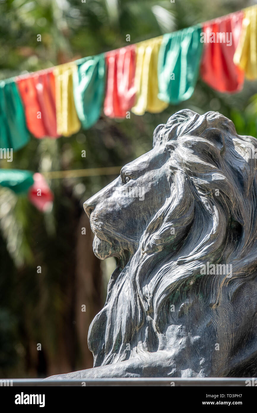 Una statua di Lion si erge con orgoglio davanti ad un banner contenente l'Etiopia di colori nazionali, Addis Abeba, Etiopia Foto Stock