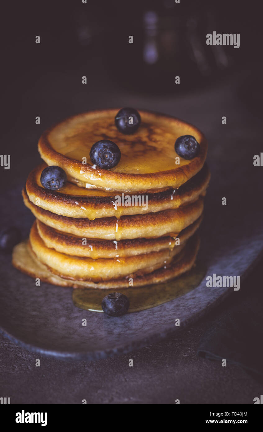 American pancake con bacche organiche e sciroppo d'acero sul Moody scuro dello sfondo. Classic colazione casalinga. Foto Stock
