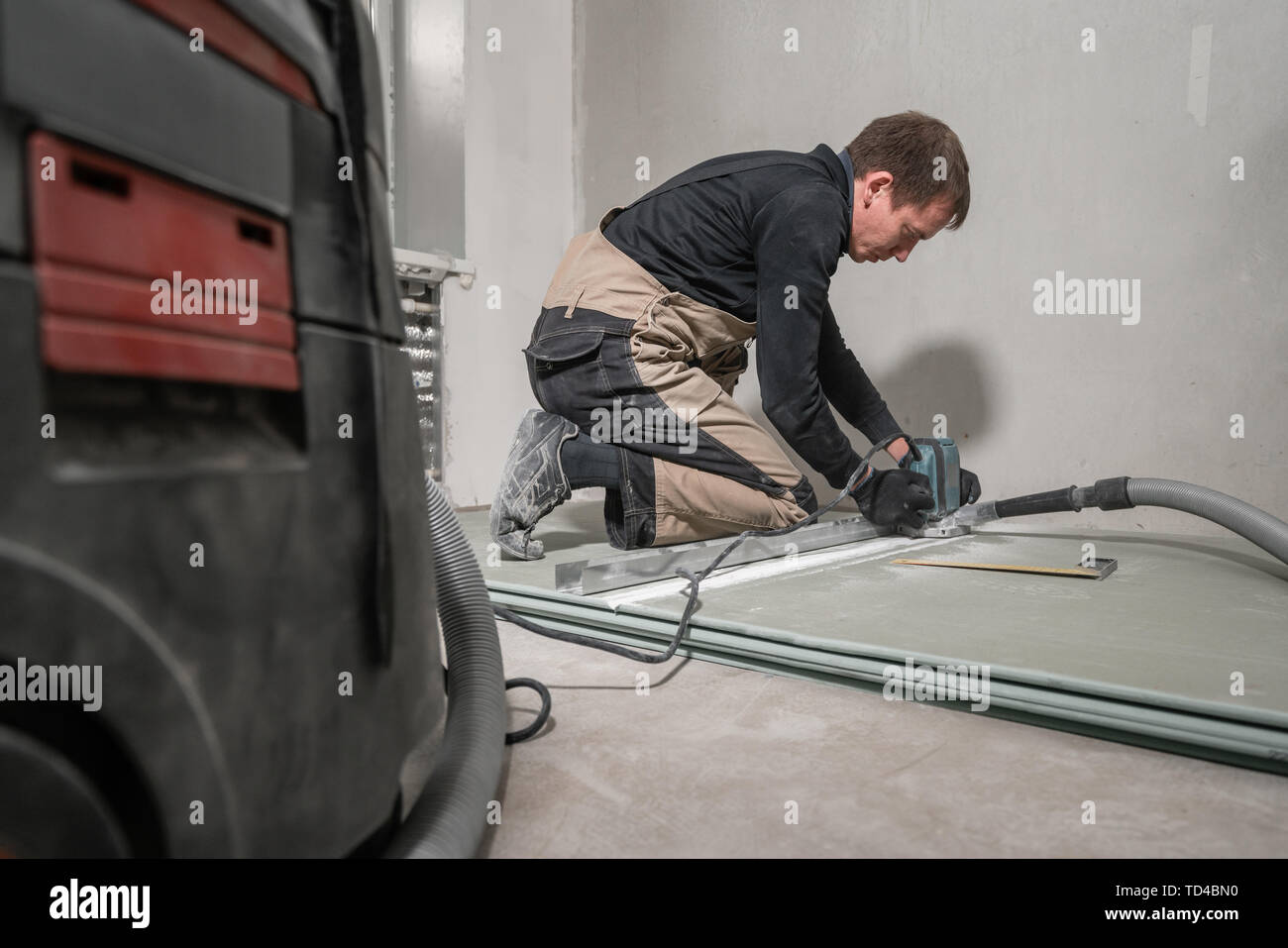 Lavoratore è utilizzando un edificio tool, utensili di fresatura e un aspirapolvere. muro a secco a novanta gradi. Foto Stock