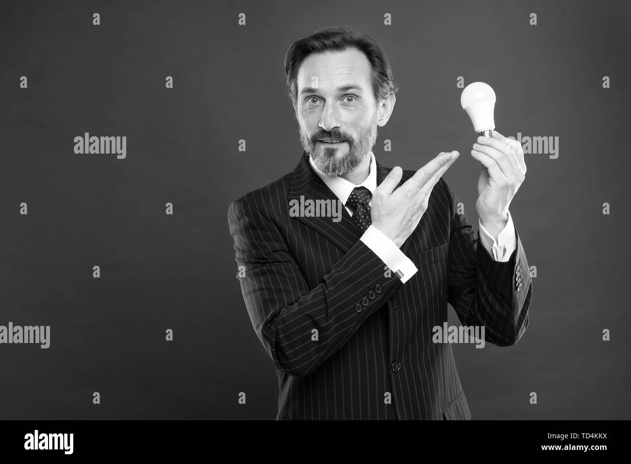 Illumina il tuo business. Uomo Barbuto imprenditore abito formale attesa lampadina luce su sfondo rosso. Simbolo dell idea di progresso e innovazione. Idea per il business. Ambiente amichevole idea. Genius idea. Foto Stock