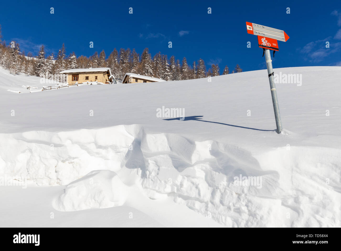 Capanne tradizionali con segnale di trekking in inverno, Livigno Valtellina, Lombardia, Italia, Europa Foto Stock