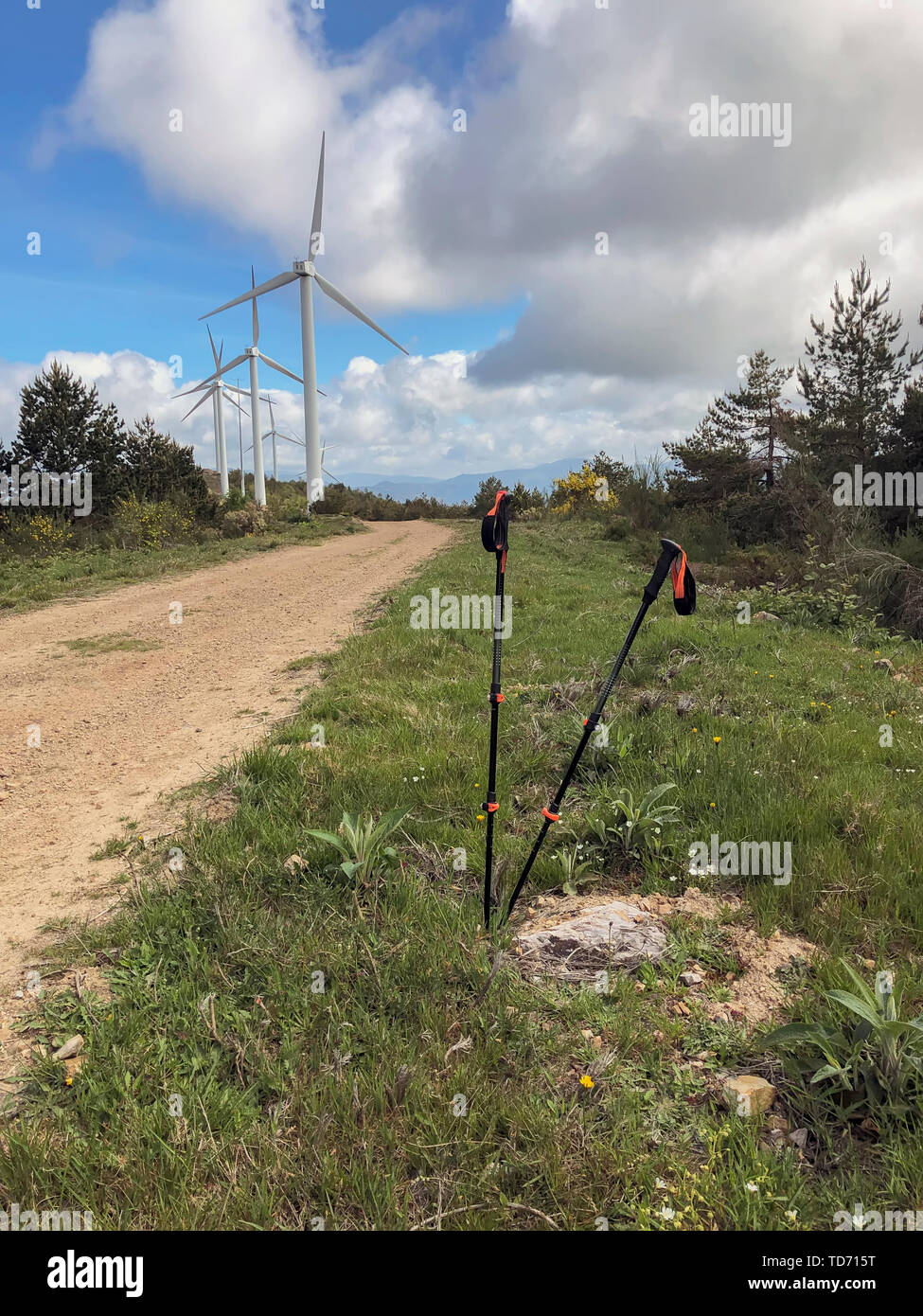 I bastoni per escursioni, bastoncini da trekking sullo sfondo della strada di terra con generatori di vento. Attivo e uno stile di vita sano in estate Foto Stock