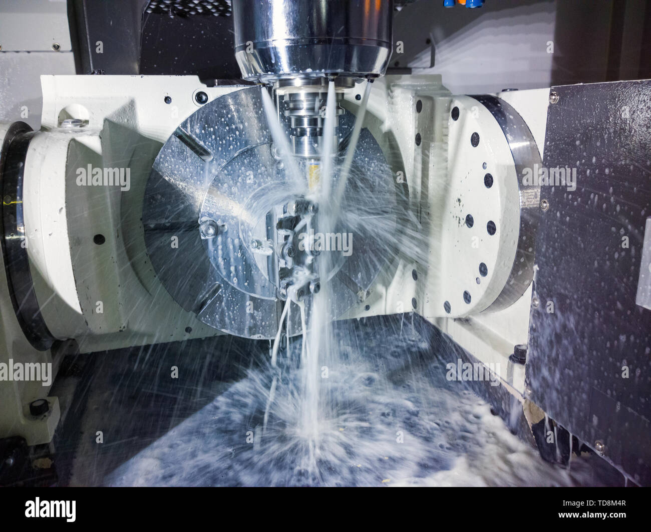 A 5 assi macchina CNC durante il lavoro con il liquido di raffreddamento sotto pressione e motion blur di torrenti.. Foto Stock