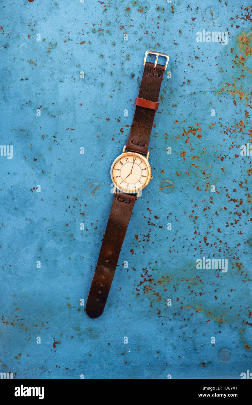 Vintage orologio da polso sul blu rustico banco di metallo suggerendo il tempo è 07.00. Foto Stock