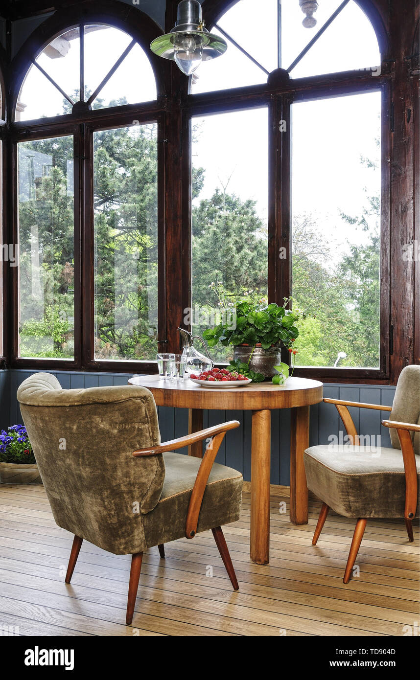Due sedie imbottite ad una tavola rotonda di fronte a finestre ad arco con vista che dà sul giardino del Regno Unito e irlandese solo diritti Foto Stock