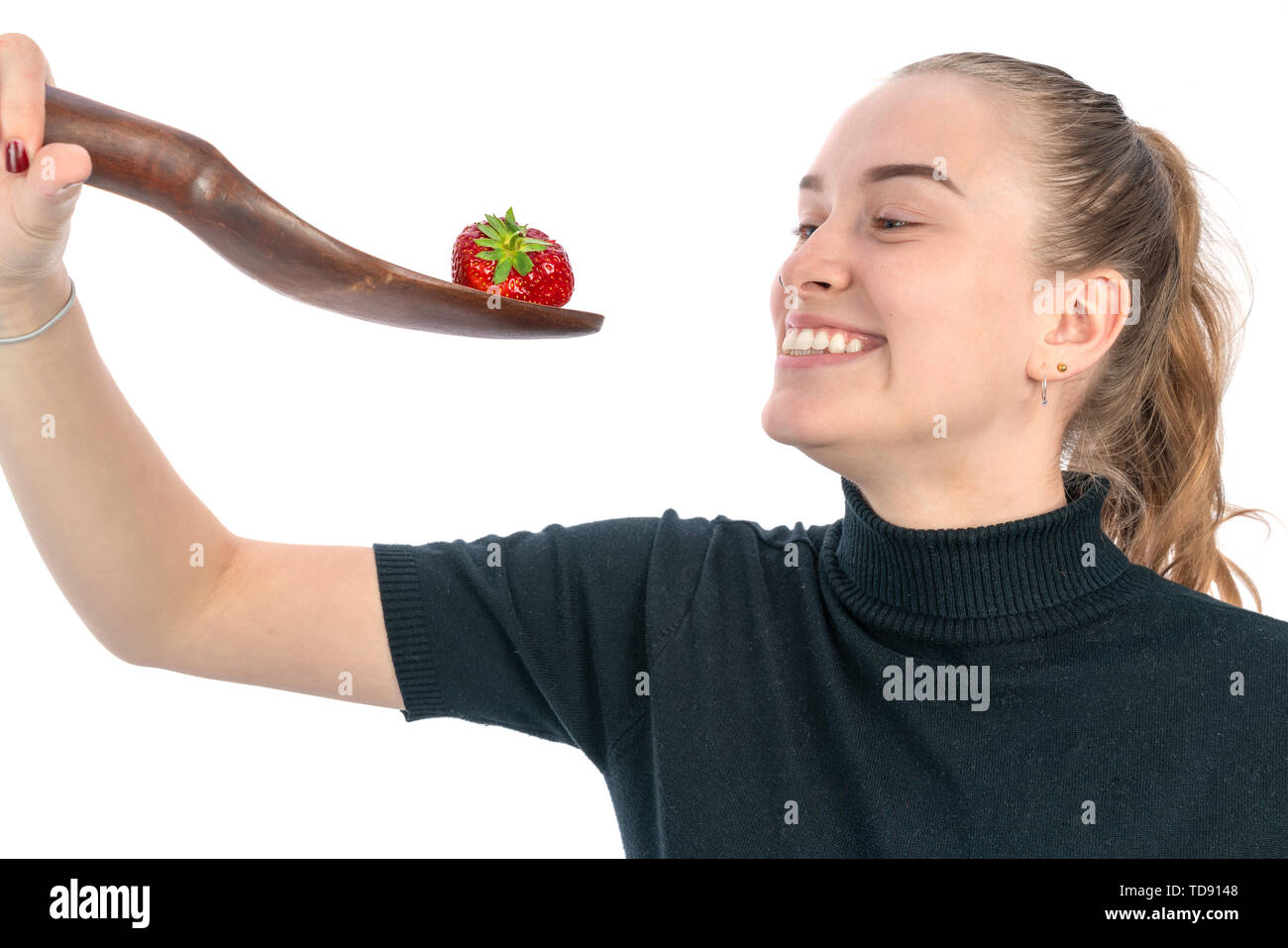 Una donna è in possesso di un grosso cucchiaio con una fragola su di esso per mangiare Foto Stock