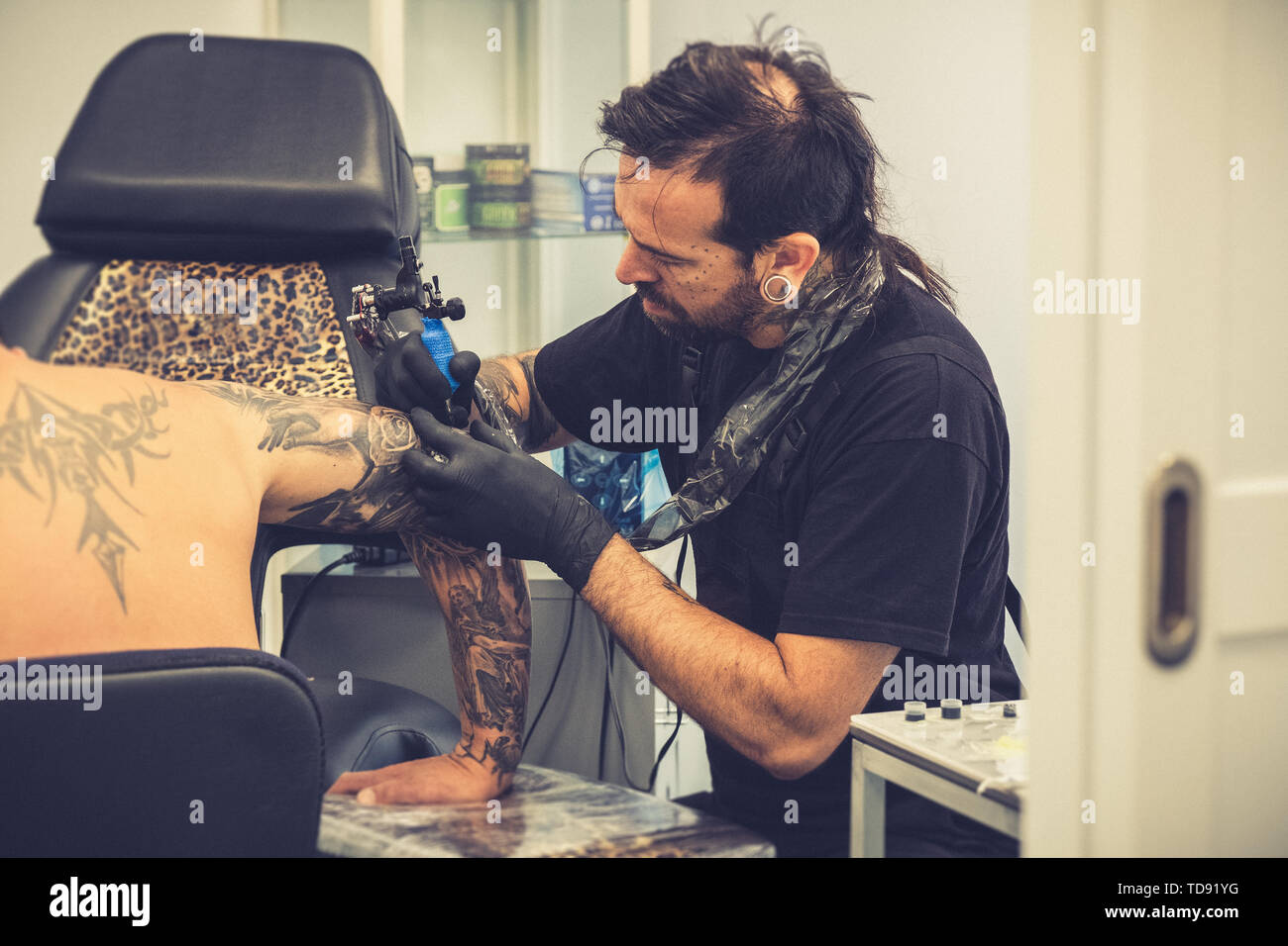Tattooist facendo un tatuaggio su un client del braccio Foto Stock