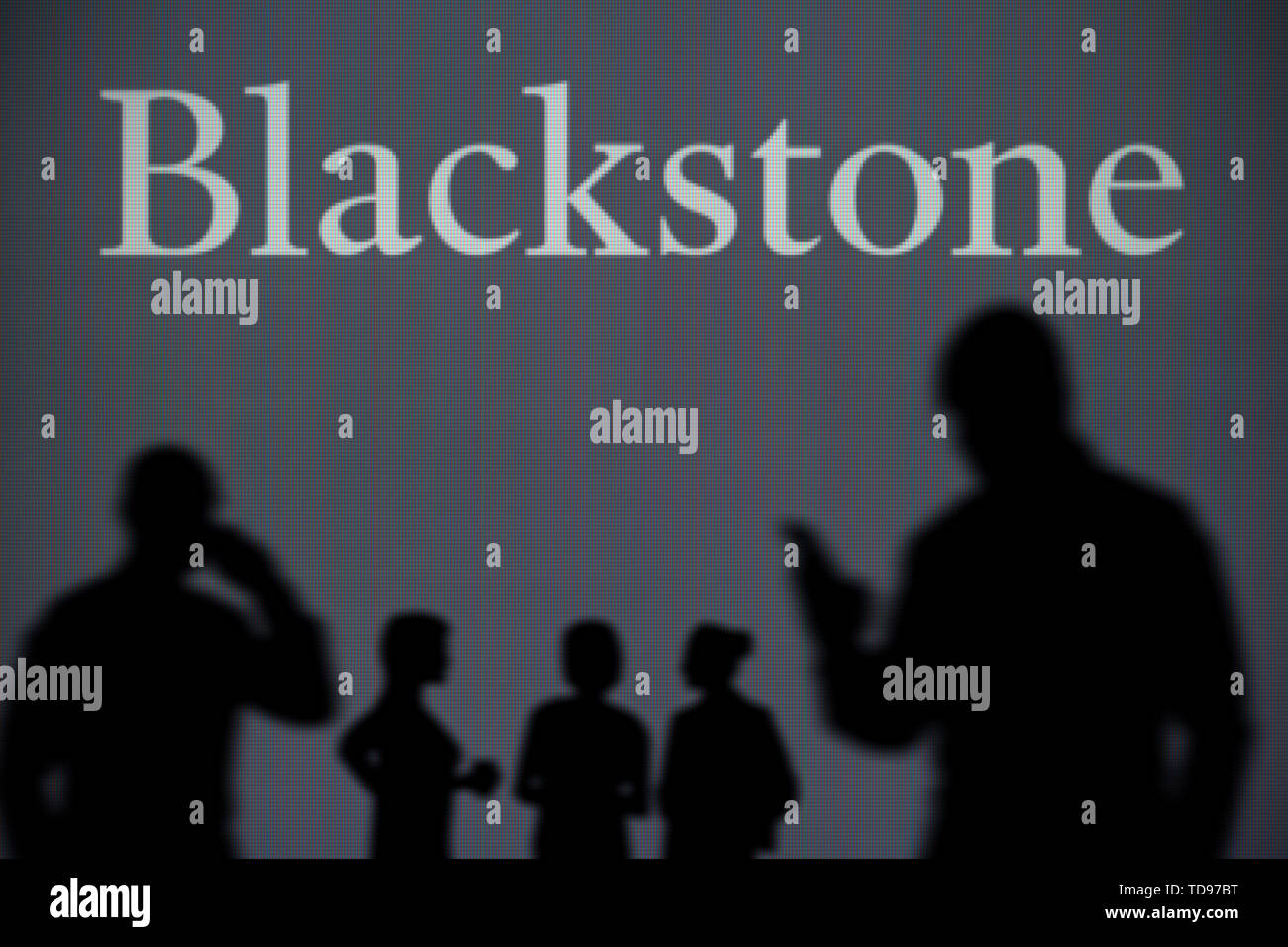 Il Blackstone logo è visibile su uno schermo a LED in background mentre si profila una persona utilizza uno smartphone in primo piano (solo uso editoriale) Foto Stock