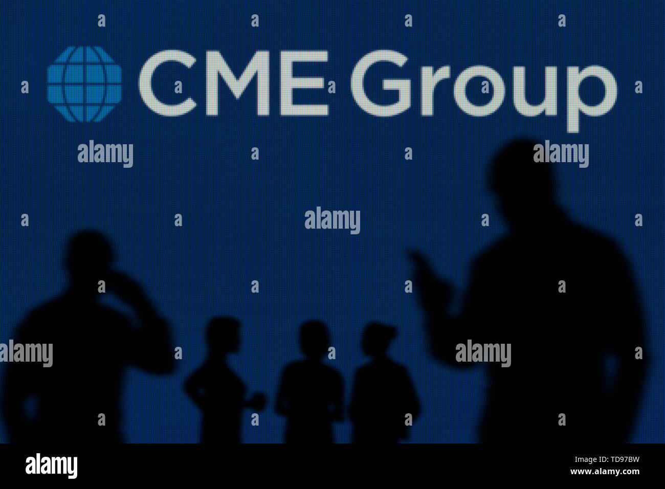 Il gruppo CME logo è visibile su uno schermo a LED in background mentre si profila una persona utilizza uno smartphone in primo piano (solo uso editoriale) Foto Stock