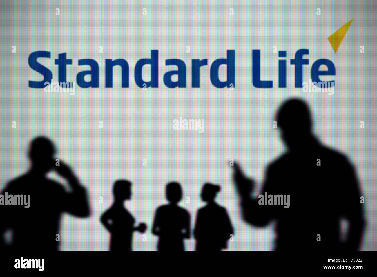 La Standard Life logo è visibile su uno schermo a LED in background mentre si profila una persona utilizza uno smartphone in primo piano (solo uso editoriale) Foto Stock