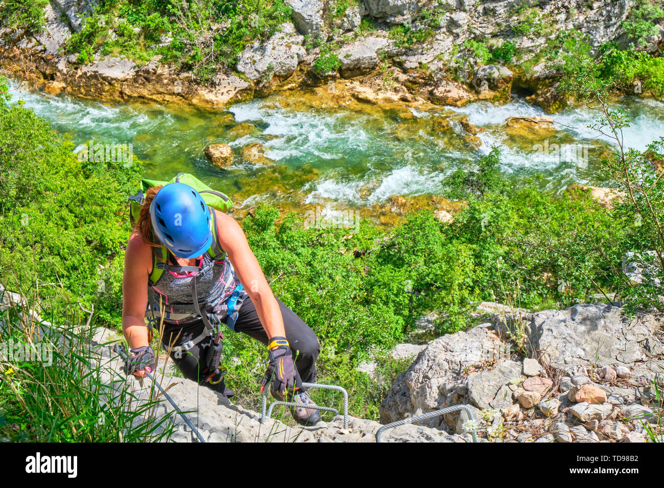 Via ferrata in Croazia, Cikola Canyon. Giovane donna salendo una media difficoltà klettersteig, con colori turchese del fiume Cikola in background. Foto Stock