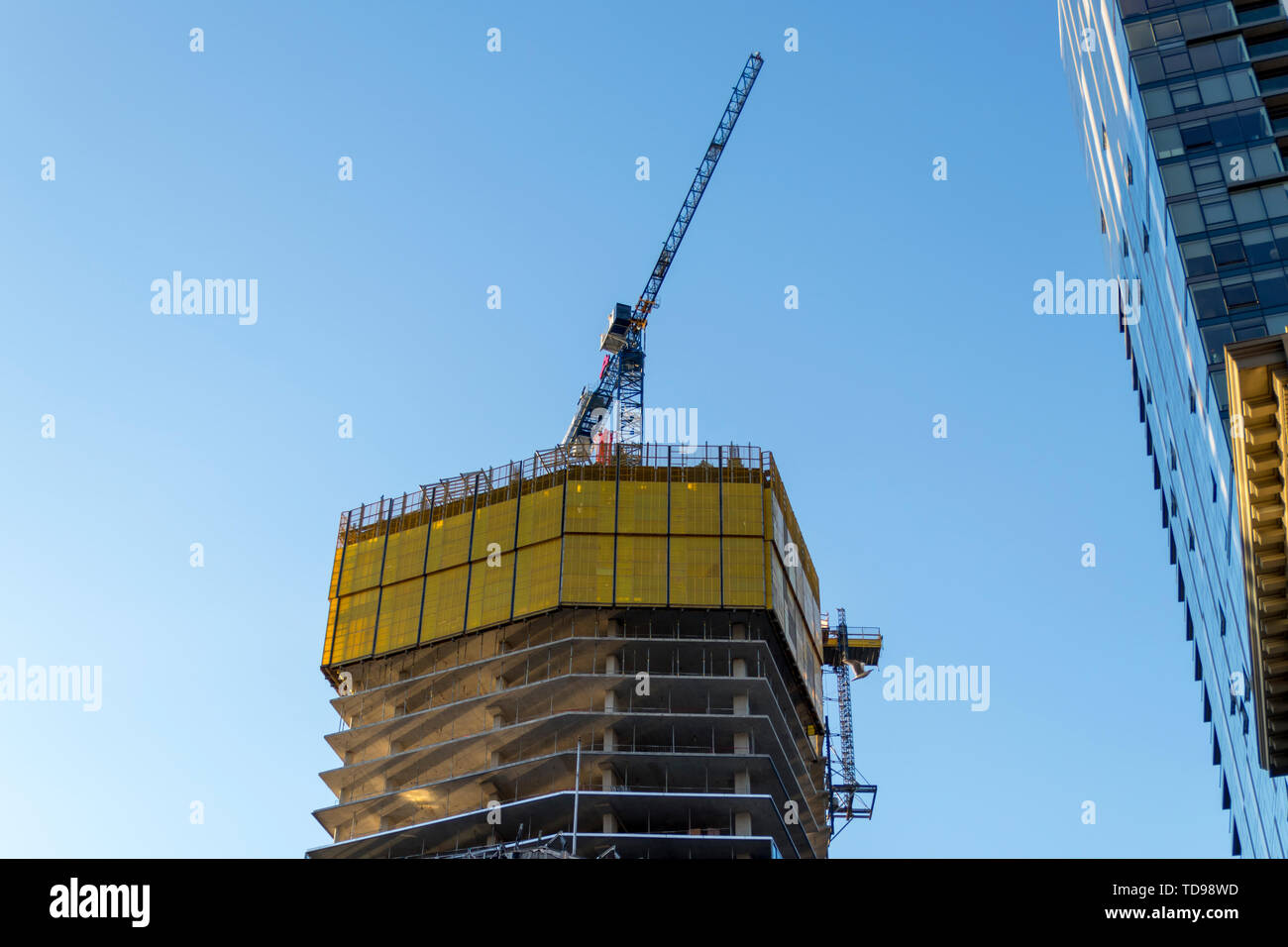 La costruzione in corso su un alto edificio e una gru sul tetto dell'edificio. Foto Stock