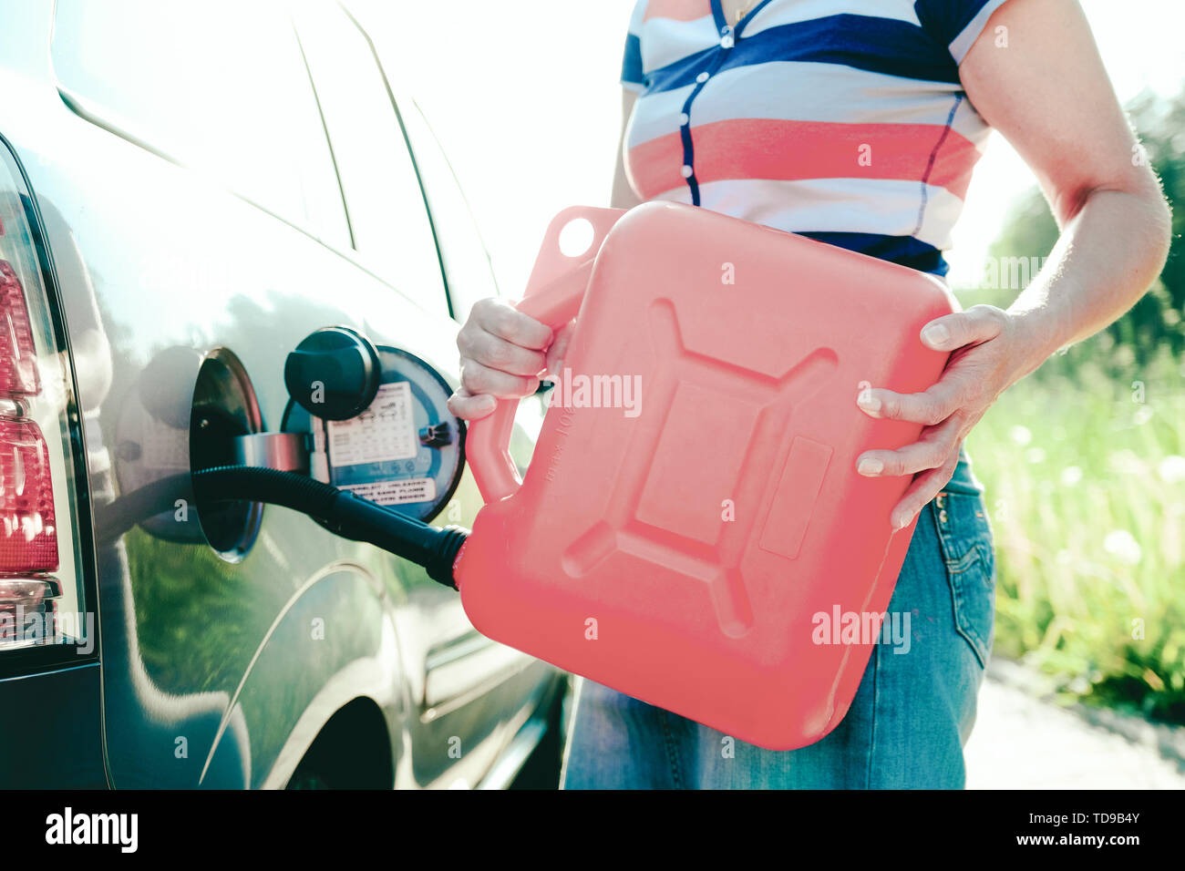 Stop forzato. Esaurito il gas presente nel serbatoio dell'auto. Una donna riempie la vettura con la benzina da un serbatoio di riserva. Barattolo di 10 litri Foto Stock