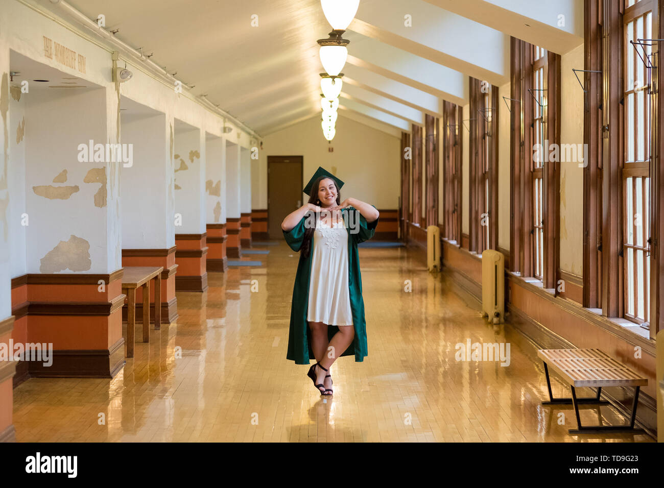 Laureato sul suo college campus in un cappuccio e camice celebrando la laurea da lei undergrad laurea durante la primavera. Foto Stock