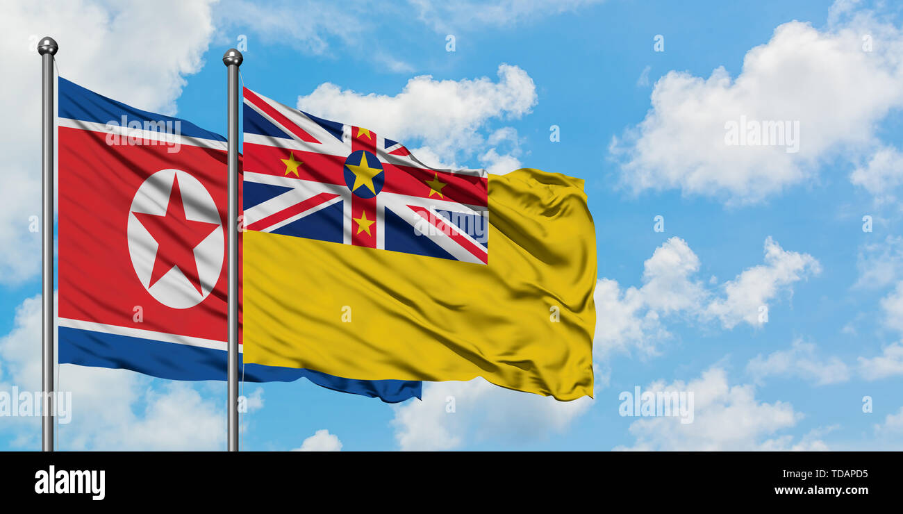 La Corea del Nord e Niue bandiera sventolare nel vento contro bianco torbido cielo blu insieme. Concetto di Diplomazia e relazioni internazionali. Foto Stock