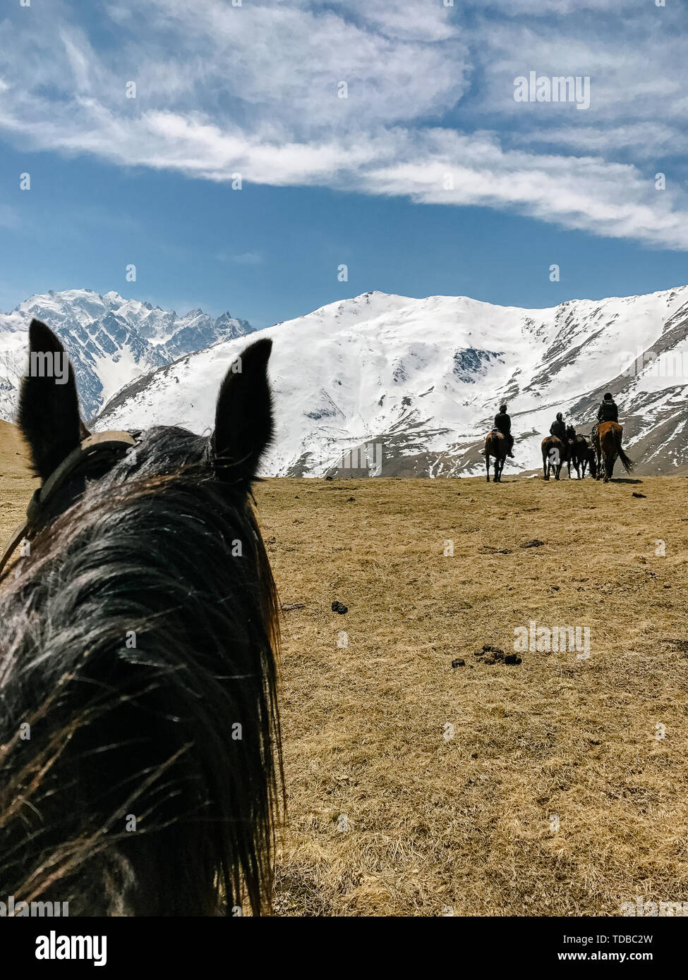 In sella ad un cavallo di prima persona la vista delle montagne e del cielo Foto Stock