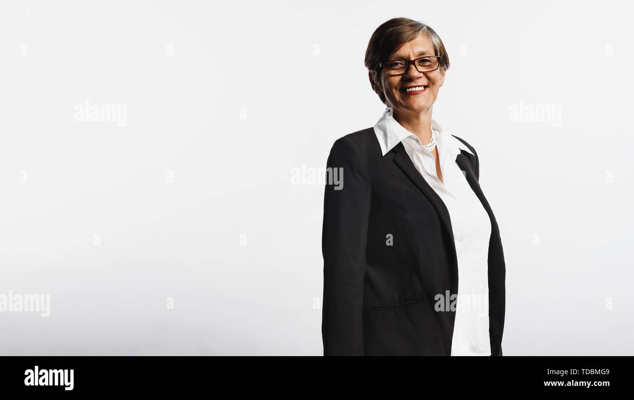 Senior donna isolato su sfondo bianco guardando la fotocamera. Sorridente donna senior in business formale usura. Foto Stock