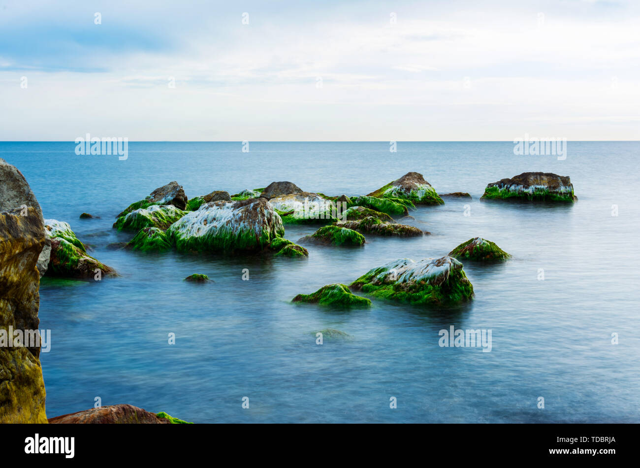 Pietre ricoperto con moss in un mare in un giorno di estate, seascape. Foto Stock