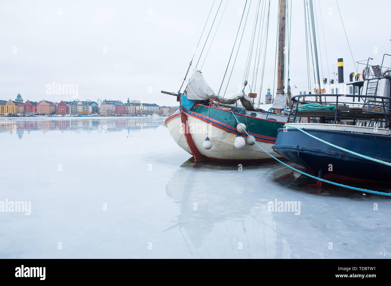 Vista invernale di Kungsholmen, Stoccolma guardando attraverso il lago ghiacciato con barche ormeggiate in primo piano. Foto Stock