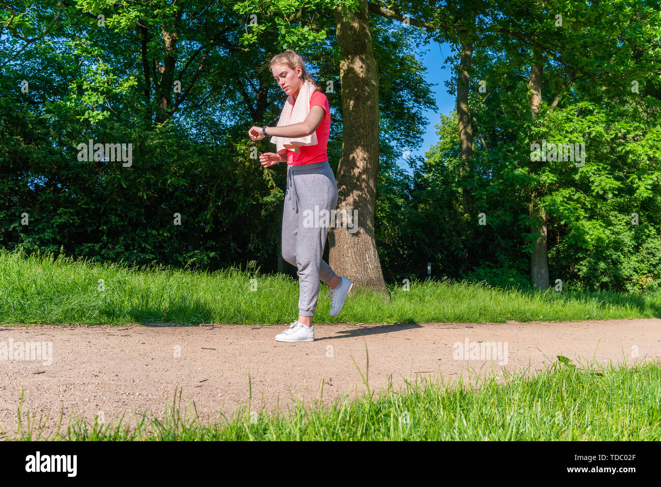 Una donna è in esecuzione nella natura e controlla il suo impulso sul suo orologio fitness Foto Stock