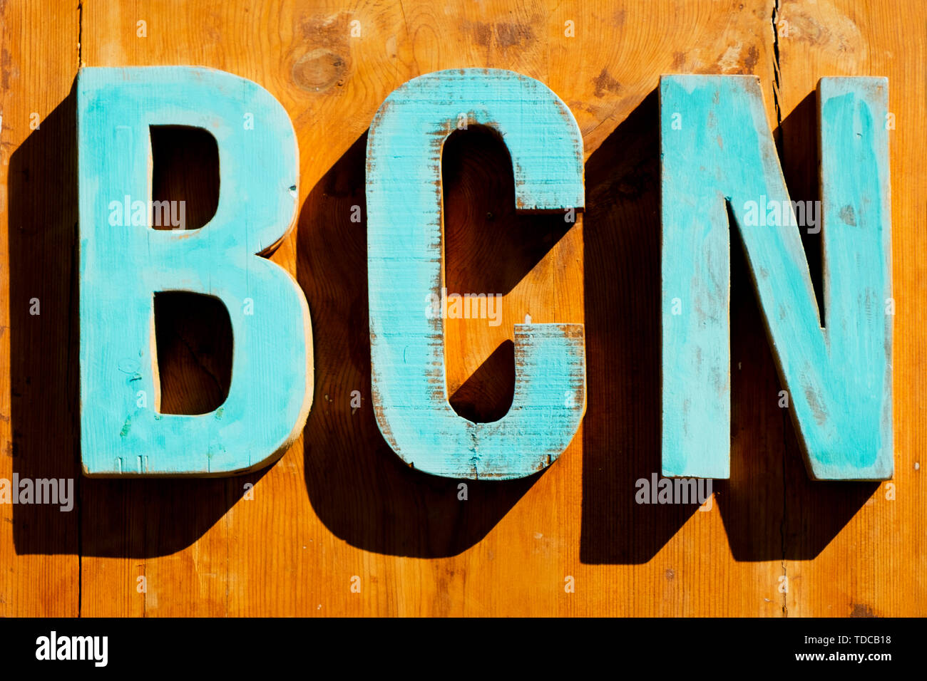 Pale in legno di colore blu tridimensionale di lettere che compongono il testo BCN, abbreviazione di Barcellona, Spagna, su uno sfondo di legno Foto Stock