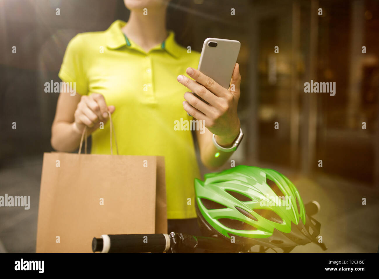 Giovane donna in maglia gialla erogazione di pacchetto utilizzando i gadget per via ordine presso la città della strada. Corriere on-line utilizzando app per ricevere il pagamento e il tracking spedizioni indirizzo. Le moderne tecnologie. Foto Stock