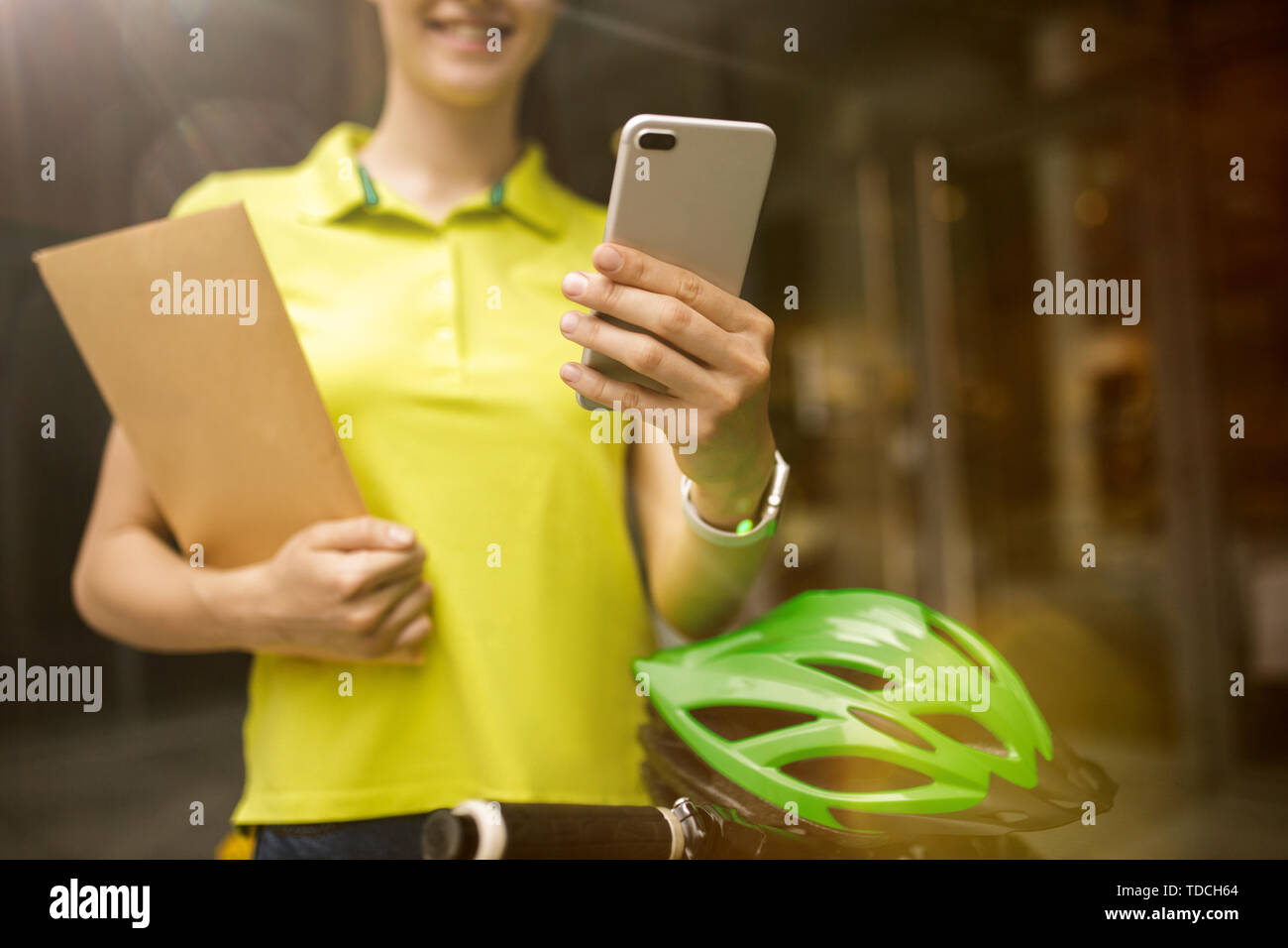 Giovane donna in maglia gialla erogazione di pacchetto utilizzando i gadget per via ordine presso la città della strada. Corriere on-line utilizzando app per ricevere il pagamento e il tracking spedizioni indirizzo. Le moderne tecnologie. Foto Stock
