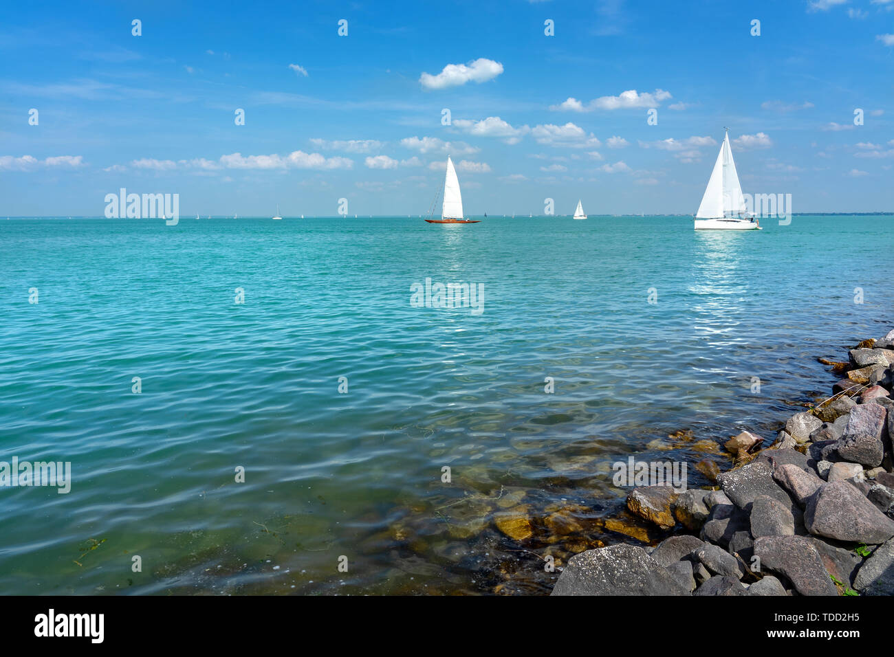 Barche a vela sul Lago Balaton con rocce sulla costa Foto Stock