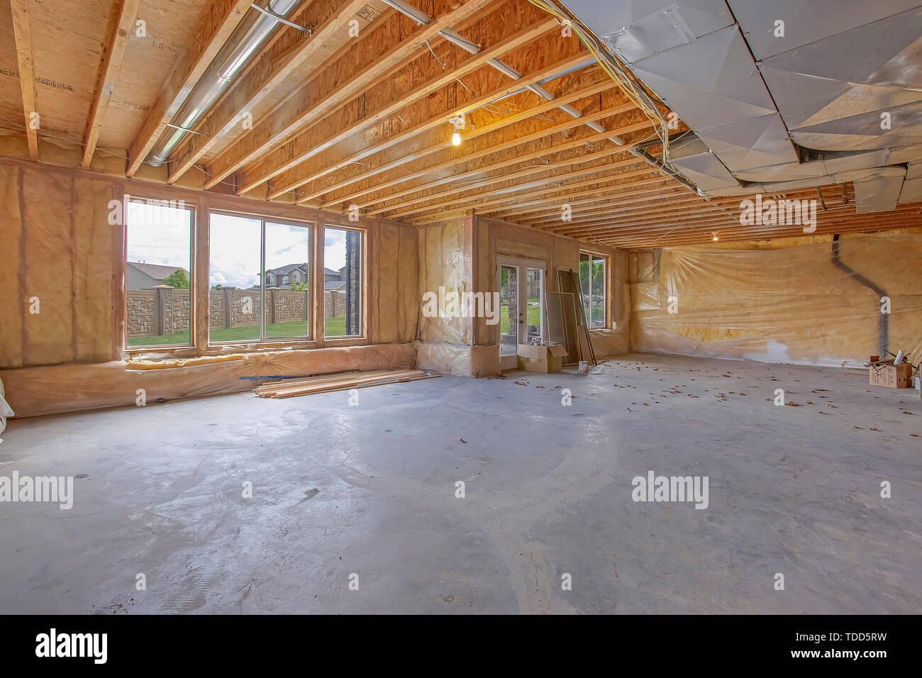 Casa non finita interno con condotti di aria condizionata e le finestre in vetro e porta. Fogli di plastica coprire le pareti che sono in costruzione. Foto Stock