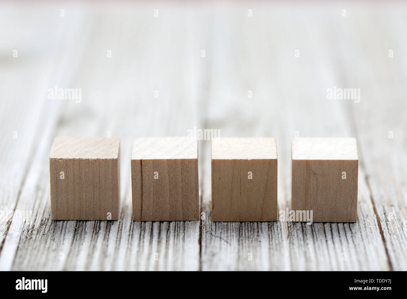 Quattro giocattolo di legno i cubi su grigio Sfondo di legno Foto Stock