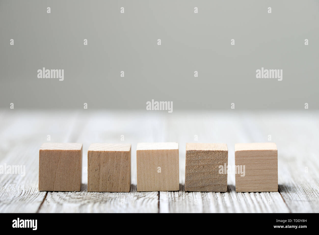 Cinque giocattolo di legno i cubi su grigio Sfondo di legno Foto Stock
