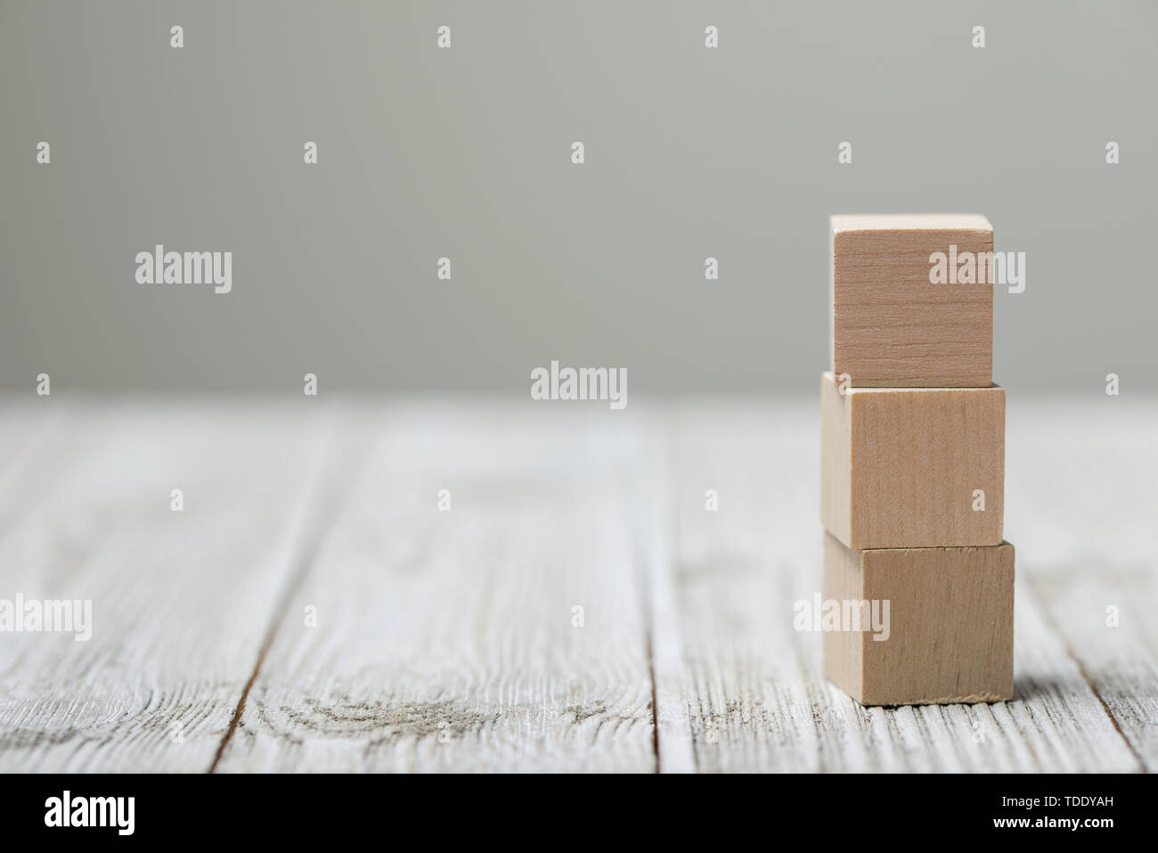 Tre giocattolo di legno i cubi su grigio Sfondo di legno Foto Stock