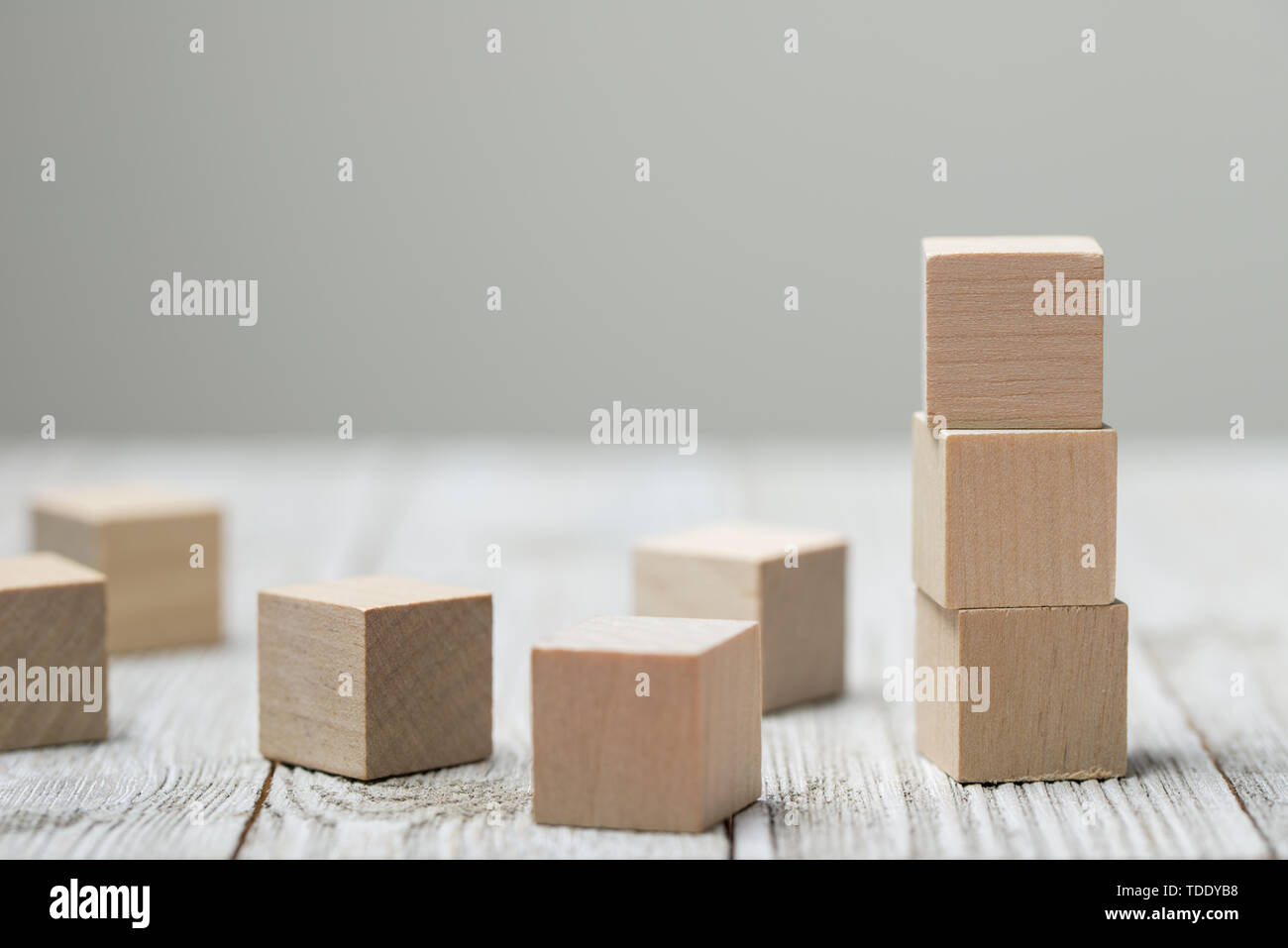 Tre giocattolo di legno i cubi su grigio Sfondo di legno Foto Stock