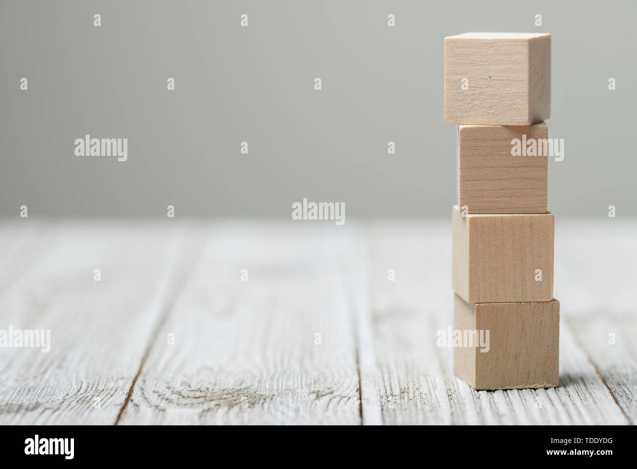 Quattro giocattolo di legno i cubi su grigio Sfondo di legno Foto Stock