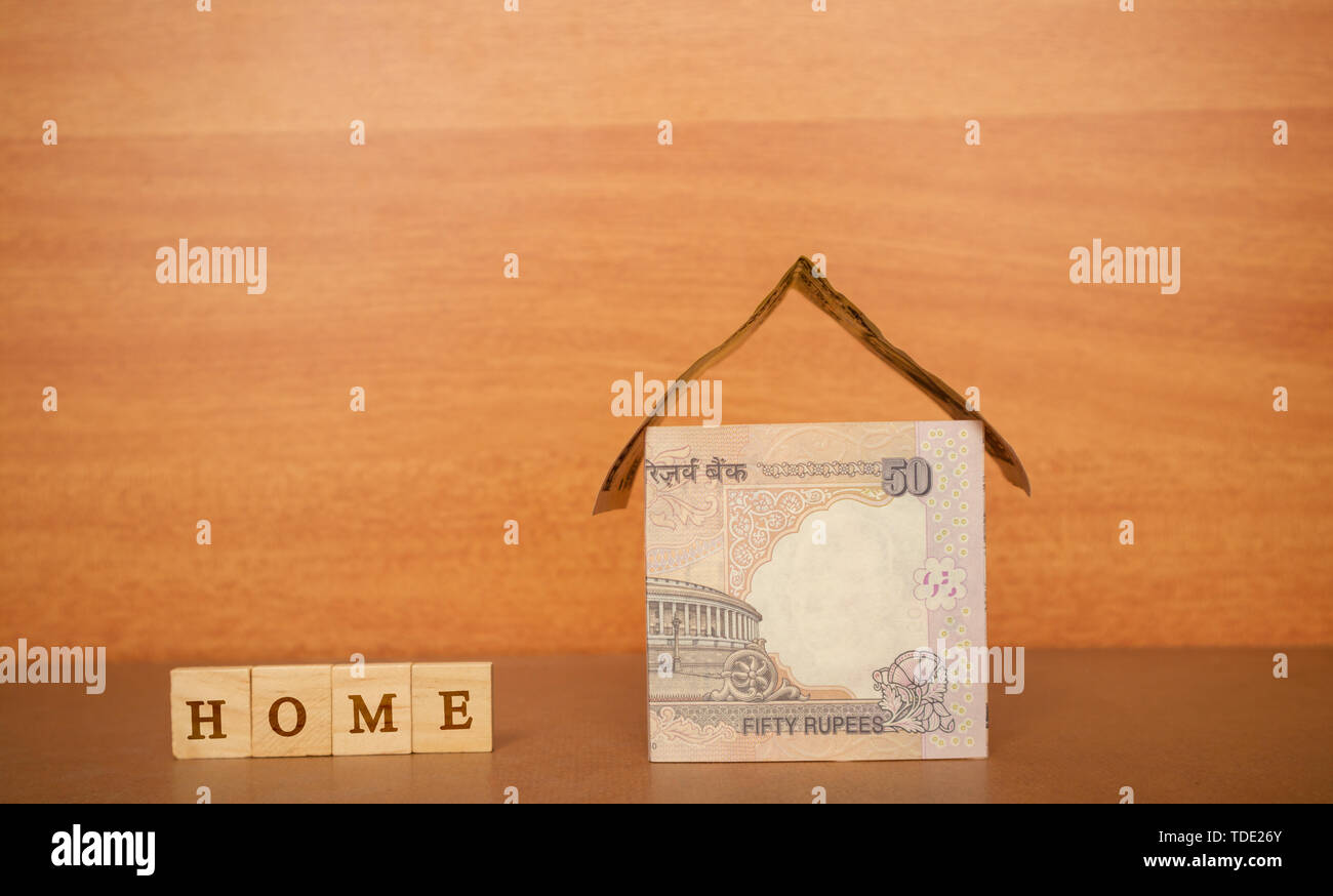 Casa fatta dalla valuta indiana note e Home prestito in blocco di legno lettere sullo sfondo di legno. Foto Stock