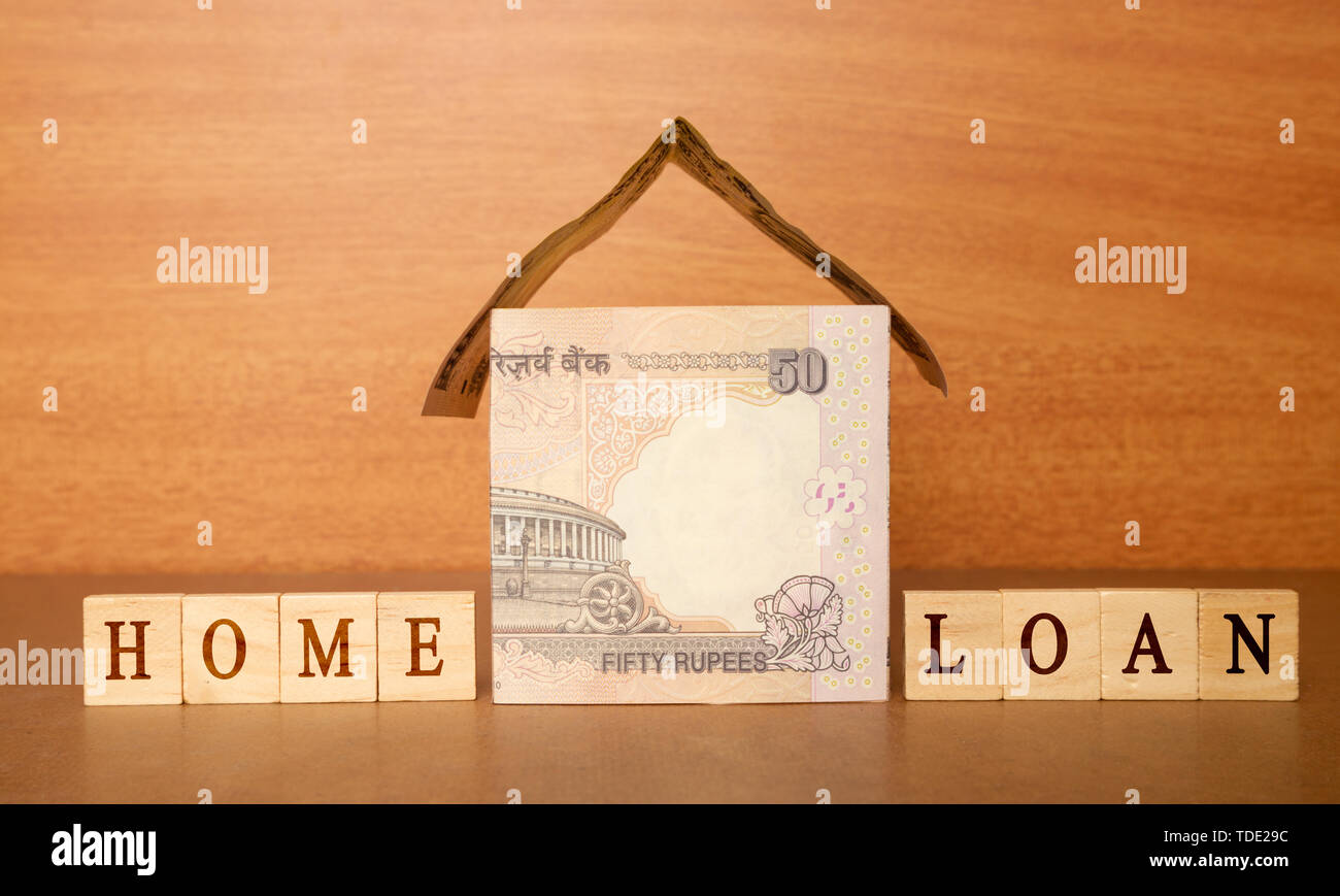Casa fatta dalla valuta indiana note e Home prestito in blocco di legno lettere sullo sfondo di legno. Foto Stock