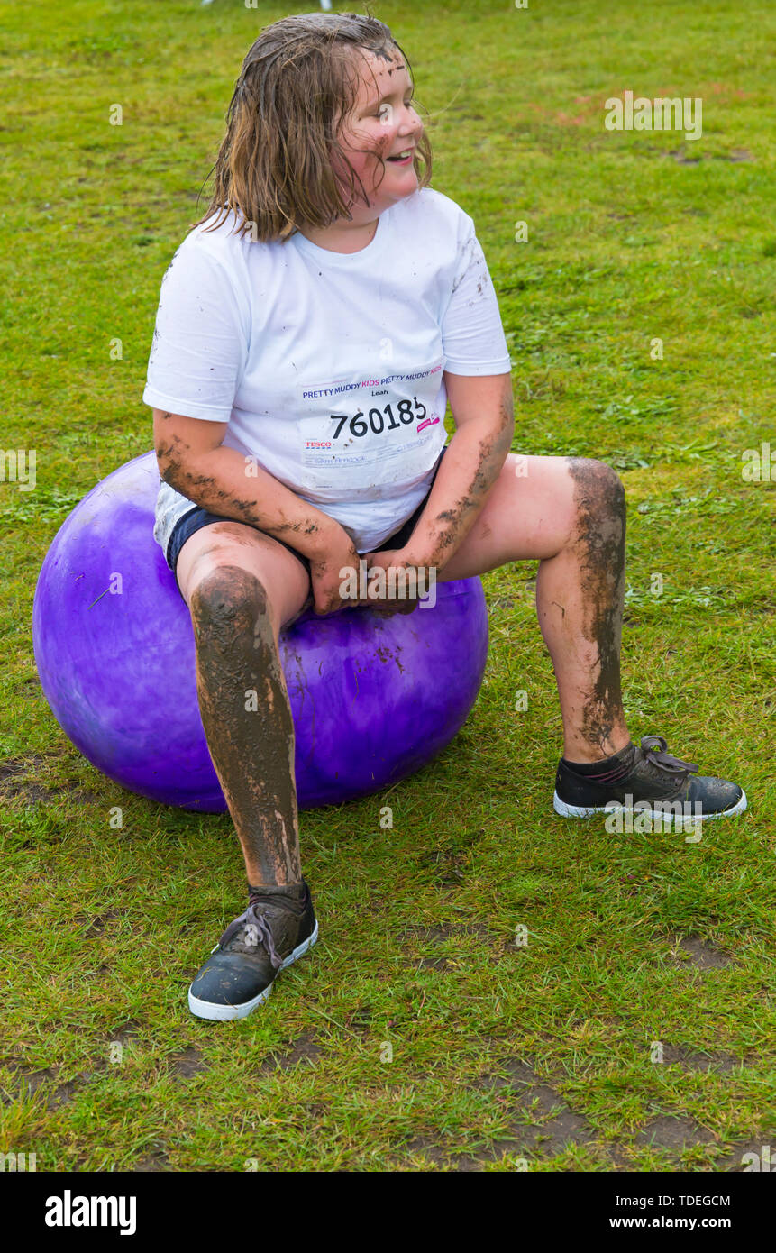 Baiter Park, Poole, Dorset, Regno Unito. Il 15 giugno 2019. Freddo umido giorno di gara per la vita piuttosto fangosa bambini dove i bambini possono unirsi nella lotta per sconfiggere il cancro e raccogliere fondi a favore della ricerca sul cancro del Regno Unito. I bambini oltre i 1,2 m di altezza e fino a 12 anni accompagnati da un adulto, negoziare gli ostacoli durante tutto il corso che è fino a 5 km e divertirsi sempre coperto di fango. Lia su spacehopper (autorizzazione ricevuta). Credito: Carolyn Jenkins/Alamy Live News Foto Stock