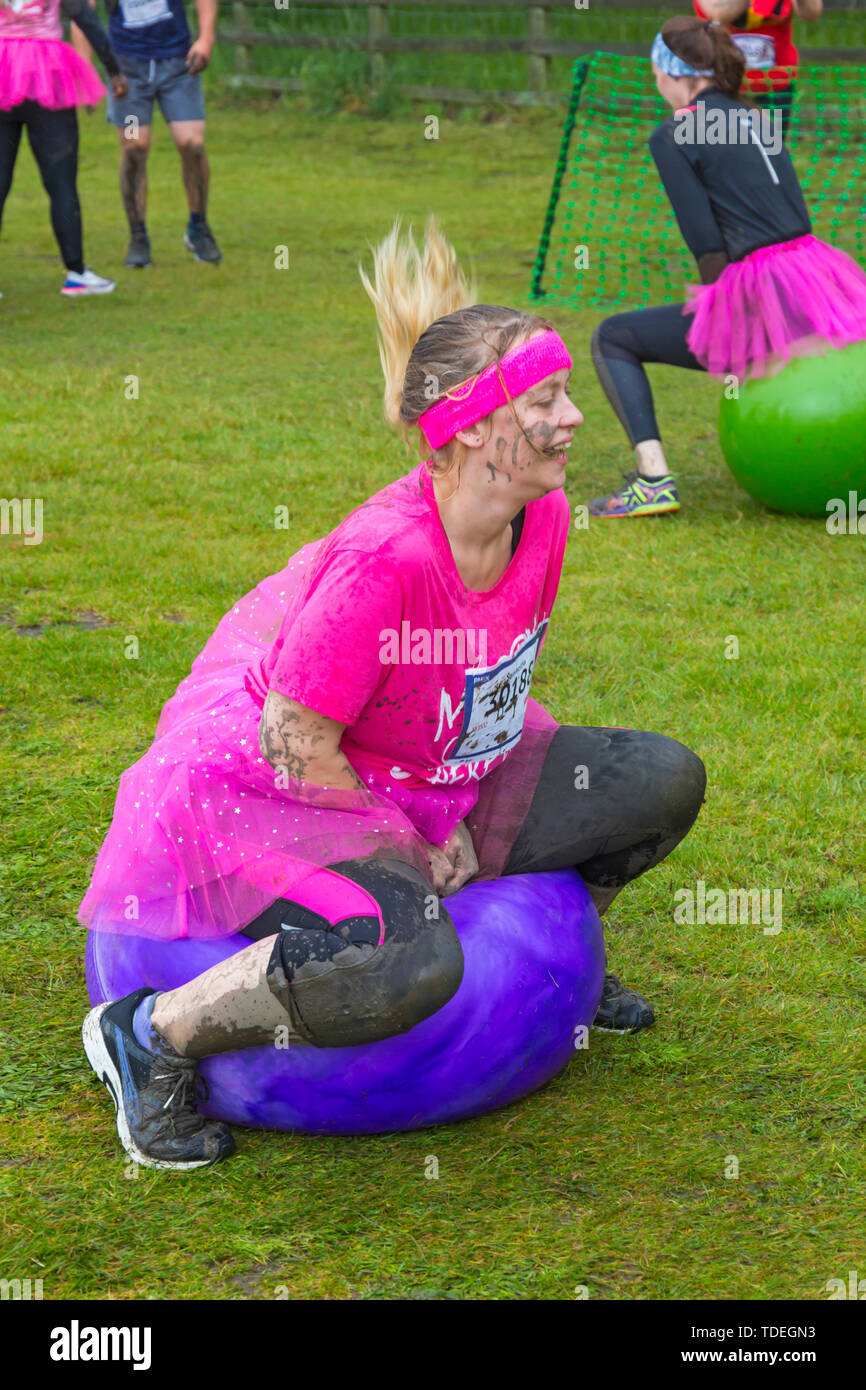 Baiter Park, Poole, Dorset, Regno Unito. Il 15 giugno 2019. Freddo umido giorno di gara per la vita piuttosto fangoso dove le donne, molti vestiti in rosa, unisciti alla lotta per sconfiggere il cancro e raccogliere fondi a favore della ricerca sul cancro del Regno Unito, il superamento degli ostacoli in tutto il 5km di corso e divertirsi sempre coperto di fango. Divertimento sulla spacehoppers! Credito: Carolyn Jenkins/Alamy Live News Foto Stock