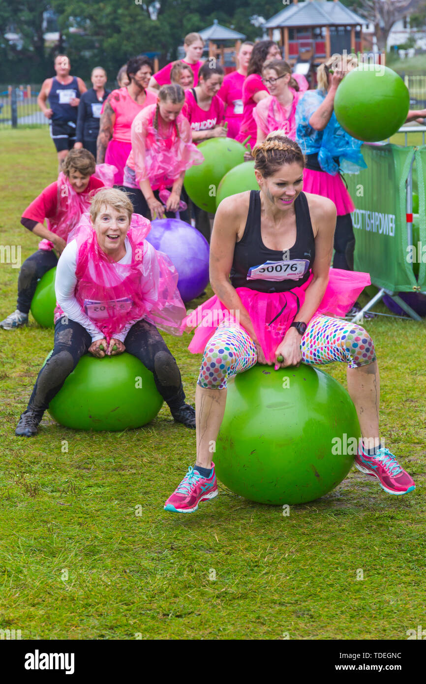 Baiter Park, Poole, Dorset, Regno Unito. Il 15 giugno 2019. Freddo umido giorno di gara per la vita piuttosto fangoso dove le donne, molti vestiti in rosa, unisciti alla lotta per sconfiggere il cancro e raccogliere fondi a favore della ricerca sul cancro del Regno Unito, il superamento degli ostacoli in tutto il 5km di corso e divertirsi sempre coperto di fango. Divertimento sulla spacehoppers! Credito: Carolyn Jenkins/Alamy Live News Foto Stock