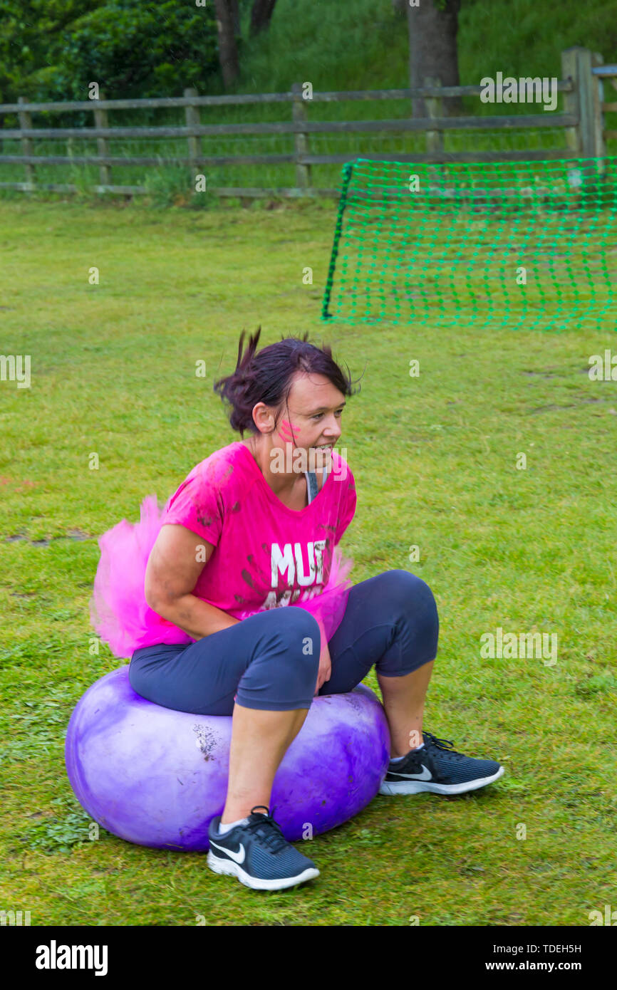Baiter Park, Poole, Dorset, Regno Unito. Il 15 giugno 2019. Freddo umido giorno di gara per la vita piuttosto fangoso dove le donne, molti vestiti in rosa, unisciti alla lotta per sconfiggere il cancro e raccogliere fondi a favore della ricerca sul cancro del Regno Unito, il superamento degli ostacoli in tutto il 5km di corso e divertirsi sempre coperto di fango. Divertimento sulla spacehoppers! Credito: Carolyn Jenkins/Alamy Live News Foto Stock