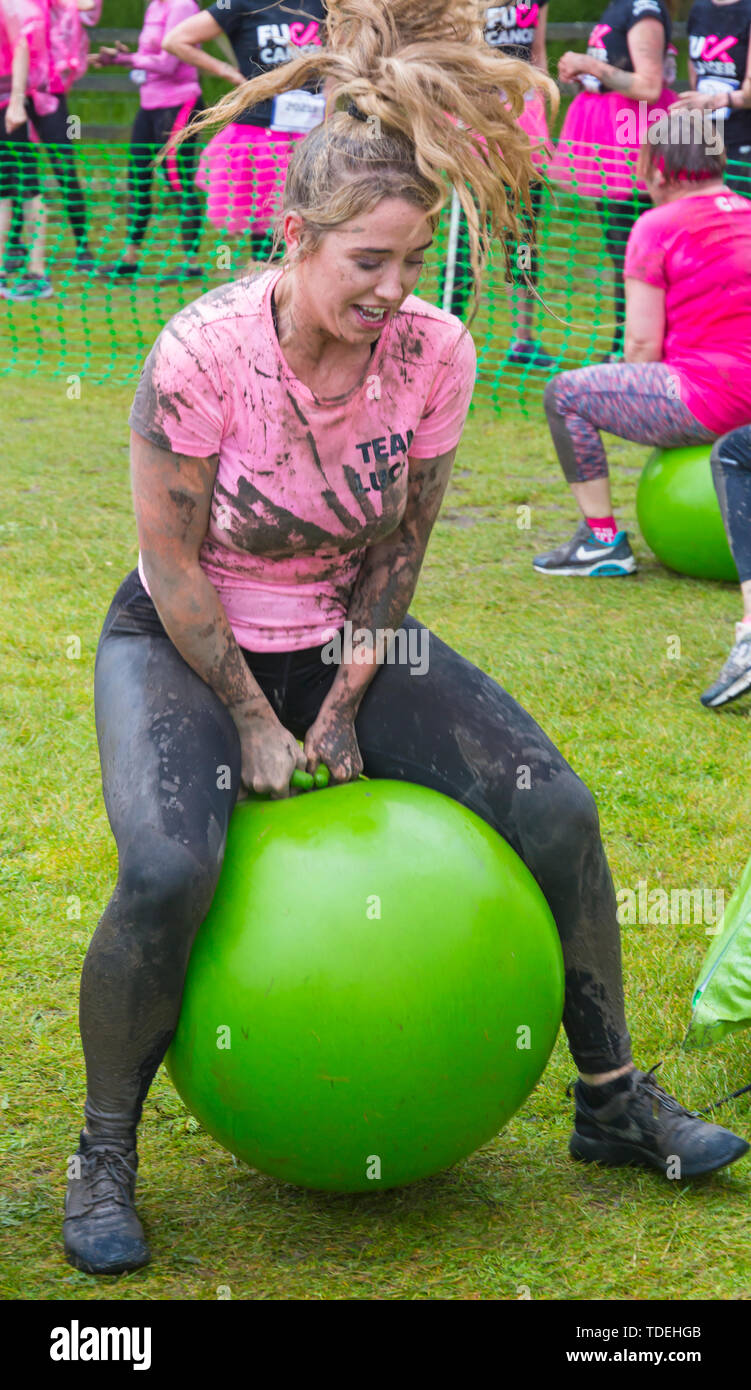 Baiter Park, Poole, Dorset, Regno Unito. Il 15 giugno 2019. Freddo umido giorno di gara per la vita piuttosto fangoso dove le donne, molti vestiti in rosa, unisciti alla lotta per sconfiggere il cancro e raccogliere fondi a favore della ricerca sul cancro del Regno Unito, il superamento degli ostacoli in tutto il 5km di corso e divertirsi sempre coperto di fango. Divertimento sulla spacehoppers! Credito: Carolyn Jenkins/Alamy Live News Foto Stock