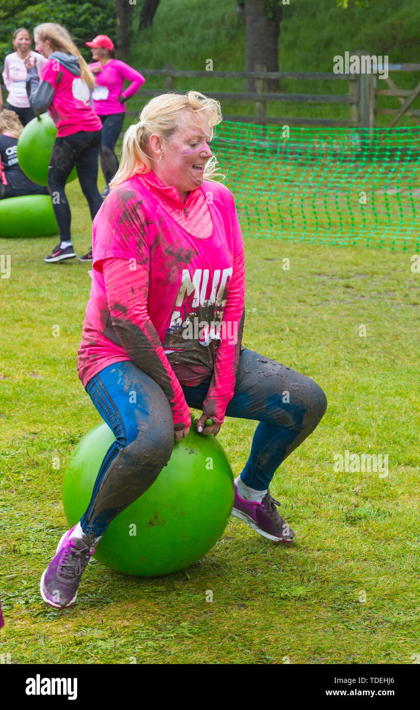 Baiter Park, Poole, Dorset, Regno Unito. Il 15 giugno 2019. Freddo umido giorno di gara per la vita piuttosto fangoso dove le donne, molti vestiti in rosa, unisciti alla lotta per sconfiggere il cancro e raccogliere fondi a favore della ricerca sul cancro del Regno Unito, il superamento degli ostacoli in tutto il 5km di corso e divertirsi sempre coperto di fango. Divertimento sulla spacehoppers! Credito: Carolyn Jenkins/Alamy Live News Foto Stock